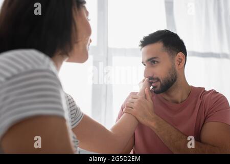 Junger Mann küsst sanft die Hand der Freundin zu Hause Stockfoto