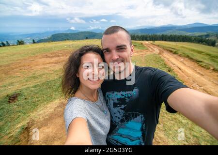 Junges Paar Umarmungen und Selfie mit erstaunlichen Berglandschaft Hintergrund. Stockfoto