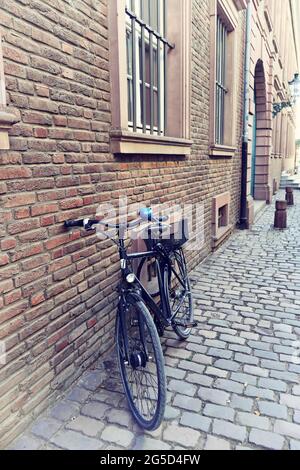 Blick auf eine Seitenstraße in der historischen Altstadt von Düsseldorf, Deutschland, mit Retro-Fahrrad, Backsteingebäude und Pflastersteinpflaster. Stockfoto