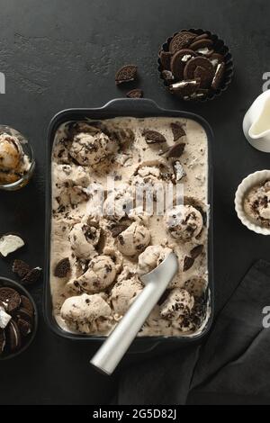 Hausgemachtes cremiges Eis und Kekse in einem Behälter auf schwarzem Hintergrund. Blick von oben. Lecker sauber essen Dessert, Zucker frei. Vertikale Orientatio Stockfoto