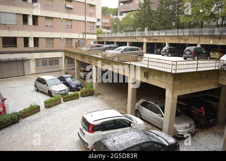 Hochwinkelaufnahme eines Wohnparkplatzes und Autos, die während eines schweren Sturms mit einer dicken Schicht weißer Hagelsteine bedeckt sind. Stockfoto