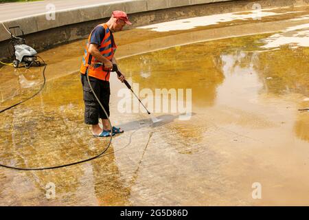 Dnepropetrovsk, Ukraine - 06.25.2021: Vorbeugende Reinigung von Stadtbrunnen im Sommer. Arbeiter säubern den angesammelten Schmutz. Stockfoto