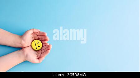 Welt Tag der psychischen Gesundheit Konzept. Hand hält blaues Papier schneiden glückliches Lächeln Gesicht, positives Denken, psychische Gesundheit Bewertung . Stockfoto