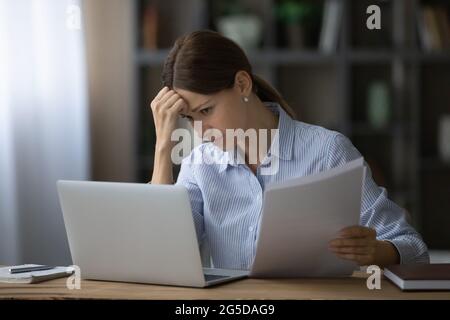 Betonte junge Geschäftsfrau, die Fehler im Finanzbericht findet. Stockfoto