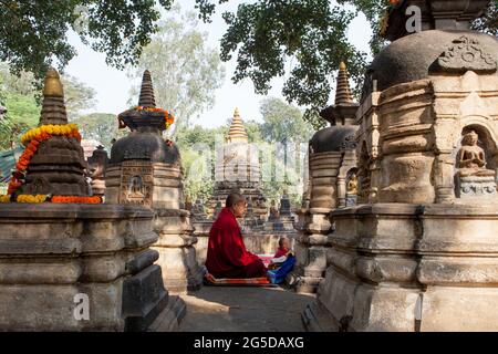 Buddhistischer Mönch, der zwischen Stupas im Mahabodhi-Tempel in Bodhgaya, Bihar, Indien, meditiert Stockfoto