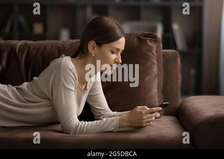 Glückliche, sorglose junge Frau, die Nachricht auf dem Smartphone tippt. Stockfoto