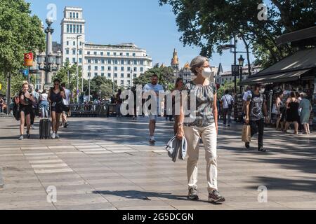 Barcelona, Spanien. Juni 2021. Eine Frau mit Gesichtsmaske geht am ersten Tag entlang der Ramblas in Barcelona, ohne die obligatorische Verwendung von Gesichtsmasken. Der Präsident der spanischen Regierung, Pedro Sanchez, kündigte am 18. Juni an, dass die Verwendung von Schutzmasken in Außenumgebungen ab Juni 26 nicht mehr obligatorisch sein wird, nachdem sie von einem außerordentlichen Ministerrat genehmigt wurde. Kredit: SOPA Images Limited/Alamy Live Nachrichten Stockfoto