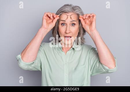 Porträt der attraktiven erstaunt grauhaarige Frau Nachrichten Reaktion wow isoliert über grauen Pastellfarben Hintergrund Stockfoto