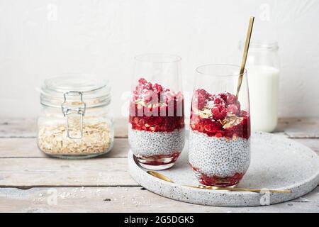 Zwei Gläser Chia Pudding mit Müsli und Himbeeren. Stockfoto