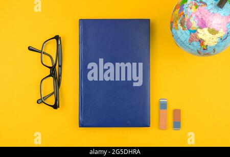 Geographie Bildung flach lag und mockup Hintergrund mit dem Globus und leeres blaues Buch, Gläser auf dem Tisch, Draufsicht Stockfoto