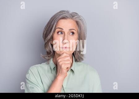 Foto von nachdenklich gesinnten ernst reifen Frau suchen Copyspace Denken träumen isoliert auf grauem Hintergrund Stockfoto
