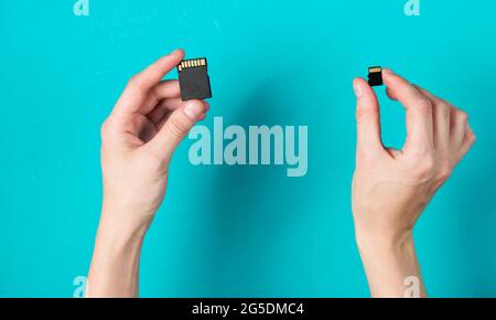 Weibliche Hände halten zwei SD-Speicherkarten auf blauem Hintergrund. Minimalistisches Techno-Konzept. Draufsicht Stockfoto
