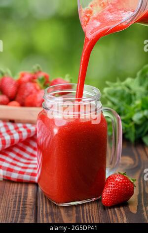 Erdbeersaft aus der Kanne in das Glas gießen Stockfoto