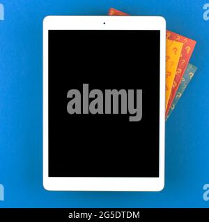 Quiz Hintergrund und Mockup mit digitalem Tablet auf blauem Desktop und Buch mit Fragezeichen, Draufsicht Stockfoto