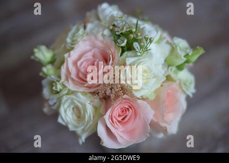 Rundes Brautstrauß mit Blick nach vorne, mit selektivem Fokus auf pinkfarbenen und weißen Rosen und verschwommenem Holzhintergrund, Blumenarangement für die zukünftige Braut Stockfoto