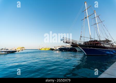 Leere Pier ohne Menschen mit einem Segelboot mit modernen Schiffen und Booten im Roten Meer Ägypten Hurghada Stockfoto