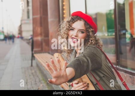 Weibliches Model im trendigen Outfit posiert auf der Straße und sagt Hallo oder Tschüss Stockfoto