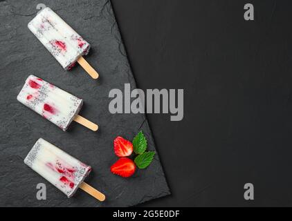 Drei Eiscremes mit frischen Erdbeeren und Chiasamen auf schwarzem Hintergrund. Gesundes Sommerdessert. Stockfoto