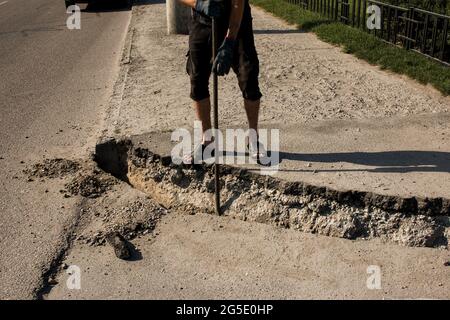 Der Prozess der Verlegung der Bürgersteig-Bordsteinkante. Die Arbeiter bereiten einen Graben für die Platzierung eines Betonklotz vor. Stockfoto