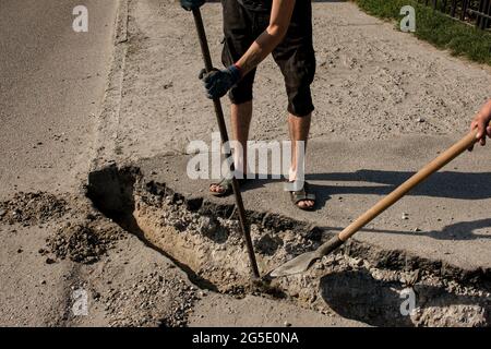 Der Prozess der Verlegung der Bürgersteig-Bordsteinkante. Die Arbeiter bereiten einen Graben für die Platzierung eines Betonklotz vor. Stockfoto