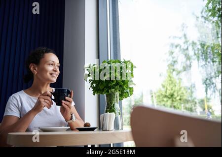 Attraktive afroamerikanische Frau genießt Kaffeepause im Café. Frau trinkt Kaffee Stockfoto
