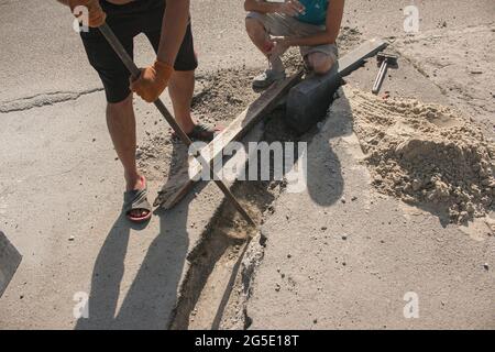 Der Prozess der Verlegung der Bürgersteig-Bordsteinkante. Die Arbeiter bereiten einen Graben für die Platzierung eines Betonklotz vor. Stockfoto