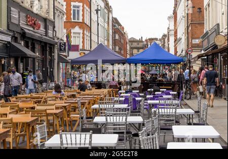 Tische und Stühle zum Essen und Trinken im Freien in den Cafés und Bars von Soho am Tag. London - 26. Juni 2021 Stockfoto