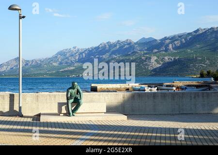 Jasenice, Kroatien. Juni 2021. Am Pier und Hafen von Rovanjska am Rande des Velebit-Gebirges, unweit von Zadar, sitzt eine Bronzefigur eines Mannes. Quelle: Peter Endig/dpa-Zentralbild/ZB/dpa/Alamy Live News Stockfoto