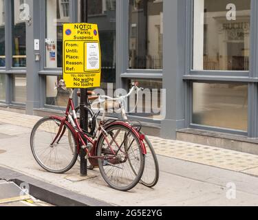 Parkplatzschild an einem Laternenpfahl mit zwei unten angeketteten Fahrrädern. London - 26. Juni 2021 Stockfoto