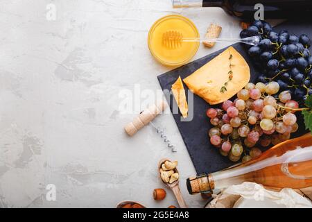 Wein-Snack-Set für Essen Party romantisches Abendessen. Rosé-Champagner Rotwein in Flaschen mit Varieté-Vorspeise auf grauem rustikalem Betontisch. Käseplatte Stockfoto