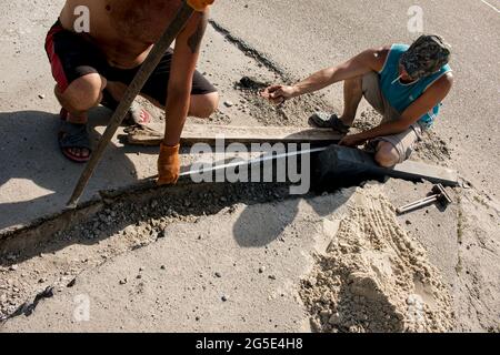 Dnepropetrovsk, Ukraine - 06.26.2021: Der Prozess der Verlegung der Bürgersteig-Bordsteinkante. Die Arbeiter messen ein Stück Beton vor dem Schneiden mit einem kreisförmigen Stockfoto