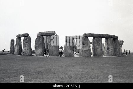 1960er, historisch, Außenansicht der Besucher bei den alten Steinen in Stonehenge, Wiltshire, England, Großbritannien. In dieser Zeit und in früheren Epochen konnte man frei um die prähistorischen Steine herumlaufen, aber in den folgenden zehn Jahren, im Jahr 1977, wurden die Steine aufgrund der steigenden Besucherzahlen und der Beschädigung des Grases und der allgemeinen Erosion an der heiligen, alten Grabstätte abgespalten, um den Zugang zu verhindern. Cecil Chubb, der sich auf dem Anwesen der Abtei von Amesbury befindet und sich zu einer Zeit im Besitz von König Heinrich VIII. War, brachte das Grundstück mit den Steinen auf einer Auktion im Jahr 1915 und gab es 1918 an die britische Nation. Stockfoto