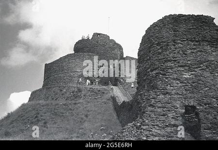 60er Jahre, historisch, Blick auf den historischen Keep und den runden Turm von Launceston Castle, Launceston, Cornwall, England, Großbritannien mit Besuchern. Das Schloss, das kurz nach der Eroberung durch die Normannen auf einem großen Naturhügel erbaut wurde, war einst der Verwaltungssitz des Grafen von Cornwall, und sein Nordgatehaus diente einst als Gefängnis. George Fox, Gründer der Quaker-Bewegung, wurde dort 1656 abgehalten. Stockfoto