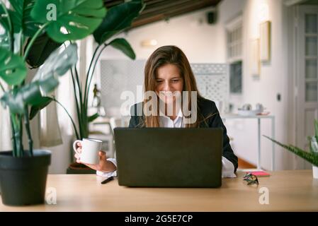 Glückliche Geschäftsfrau mit Laptop-Computer im modernen Büro - Fokus auf Gesicht Stockfoto