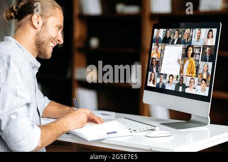Online-Schulungen. Smart kaukasischen Kerl gewinnt Wissen beobachten Lektion online. Der junge Mann notiert sich während des Webinars und hört den Vortrag über einen Videoanruf. Lehrerin und Schüler auf einem Bildschirm Stockfoto