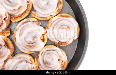 Frische Zimtbrötchen mit weißer Vereisung in einer Backform Stockfoto