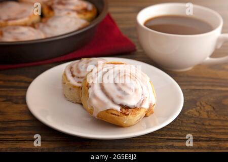 Frisch gebackene Zimtbrötchen bereit zum Frühstück mit einer Tasse Kaffee Stockfoto