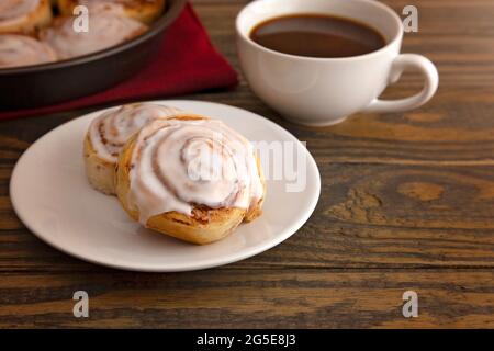 Frisch gebackene Zimtbrötchen bereit zum Frühstück mit einer Tasse Kaffee Stockfoto