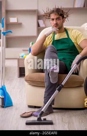 Junger männlicher Auftragnehmer, der auf dem Kopf einen stacheligen Kranz trägt und Hausarbeit leistet Stockfoto