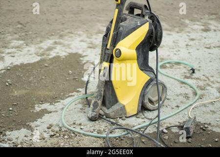 Wasserspray zur Reinigung der Maschine. Eine Waschmaschine. Eine Wasserversorgungseinrichtung. Eine elektrische Pumpe. Schmutziger Hof. Werkzeug des Gärtners. Stockfoto