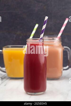 Drei Frucht-Smoothies in verschiedenen Tassen mit Papierstrohhalmen Stockfoto