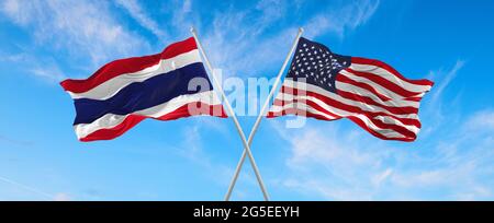 Flaggen der USA und thailands winken im Wind auf Fahnenmasten gegen den Himmel mit Wolken am sonnigen Tag. Symbolisieren Beziehung, Dialog zwischen zwei Zählen Stockfoto