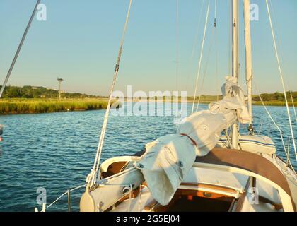 Ein Segelboot, das im frühen Morgenlicht aus Mattituck Inlet herausfährt. Long Island, NY. Kopierbereich. Stockfoto