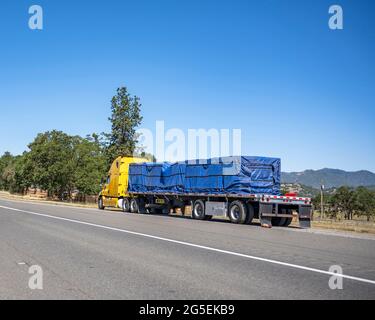 Gebrochen auf dem Weg zum Zielort gelb großen LKW mit beladenem Flachbett Sattelauflieger sitzt außer Betrieb auf der Seite einer Autobahn wai Stockfoto