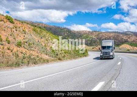 Klassische graue Motorhaube leistungsstarke große Rig Langstrecken-Industrie-Sattelschlepper Transport gewerblicher Fracht in trockenen van Sattelauflieger bergauf auf auf t Stockfoto