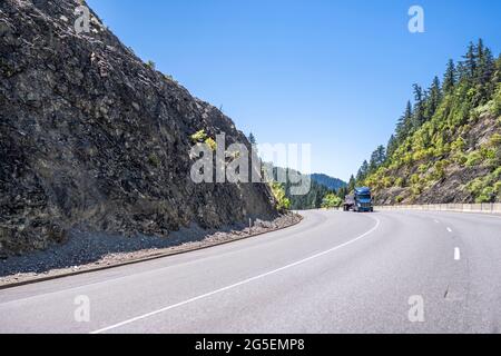 Blaue klassische Motorhaube leistungsstarke Big Rig amerikanischen Sattelschlepper mit hoher Profil Kabine Transport befestigte Ladung auf Flachbett Sattelanhänger fahren auf der w Stockfoto