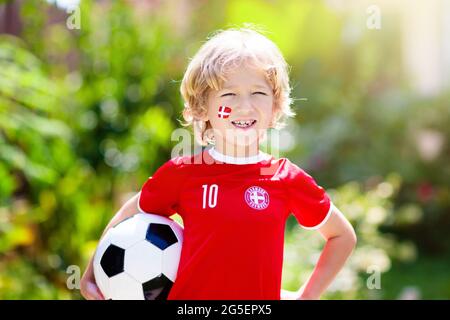 Dänemark Fußballfan jubelt. Dänische Kinder spielen Fußball und feiern den Sieg auf dem Freigelände. Danmark-Teammitglied. Kleiner Junge in Dansk Flagge Trikot Stockfoto