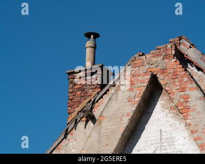 Alter Kamin auf einem sehr alten Gebäude mit einem kaputten Dach Stockfoto