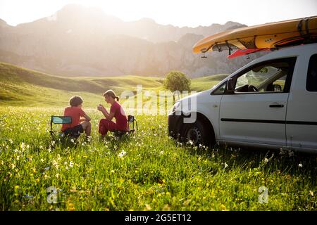 Mutter und Sohn sitzen auf Campingstühlen und frühstücken auf einem Feld voller wilder Bergblumen auf Mala Lukavica in der Nähe von Niksic, Montenegro Stockfoto