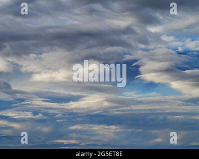 Ein surrealer und majestätischer Himmel voller weißer und grauer, hinterleuchteter Wolken, die sich gegen das Blau erheben Stockfoto